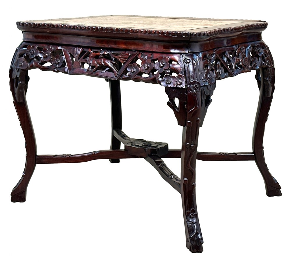 A 19th-century rectangular dark hardwood low table with an inset marble panel top, deeply carved floral apron, and cabriole legs.