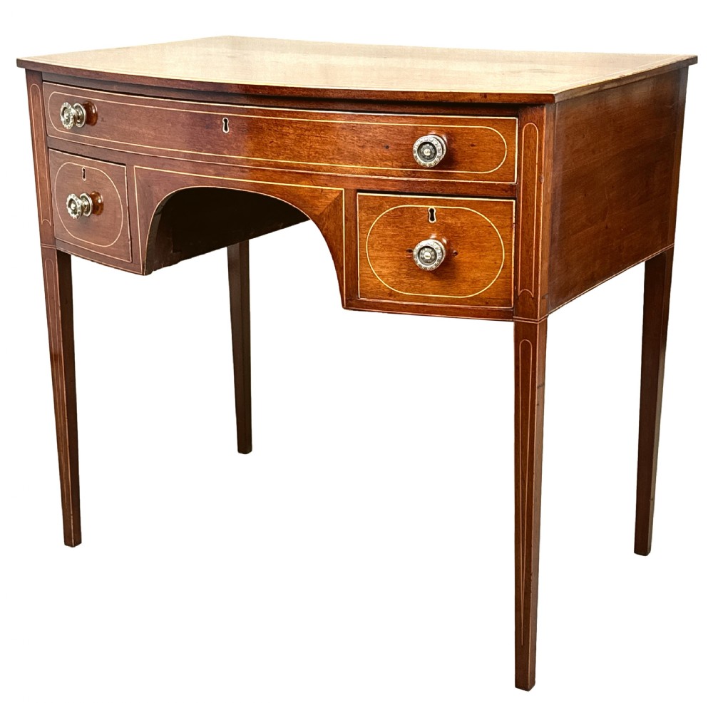 An 18th-century Georgian mahogany dressing table featuring decorative boxwood stringing, three drawers with circular knobs, an arched kneehole, and square tapered legs.