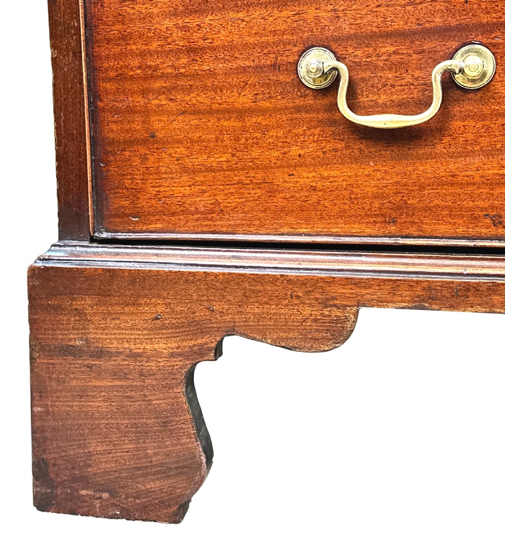 A Georgian mahogany chest of drawers featuring four graduated drawers, a pull-out brushing slide, brass swan-neck handles, and bracket feet. View X