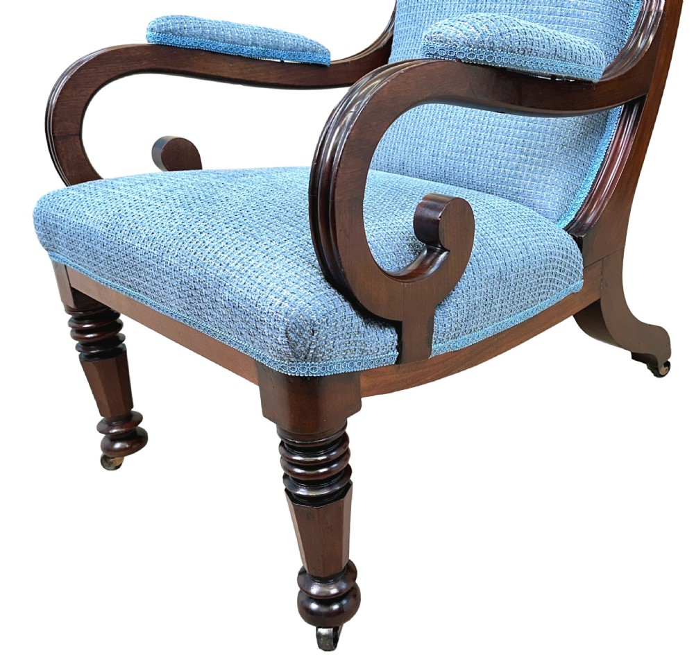A William IV mahogany library armchair featuring light blue textured upholstery, scrolled armrests, turned front legs, and brass castors. View II