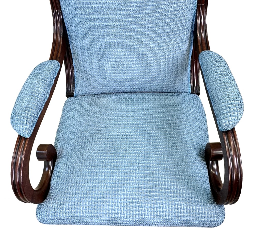 A William IV mahogany library armchair featuring light blue textured upholstery, scrolled armrests, turned front legs, and brass castors. View V