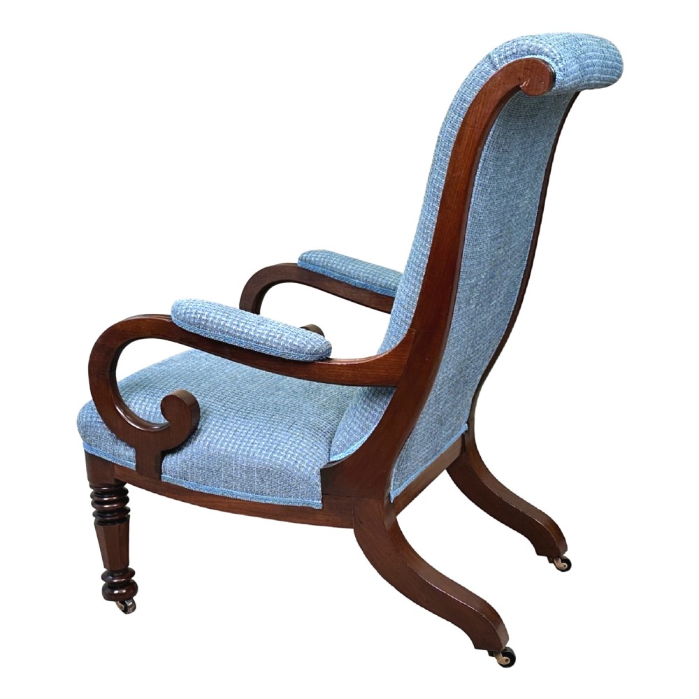 A William IV mahogany library armchair featuring light blue textured upholstery, scrolled armrests, turned front legs, and brass castors. View VI