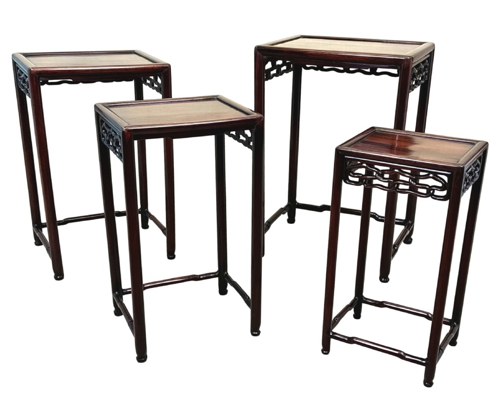 A nest of four graduated dark reddish-brown Oriental hardwood occasional tables featuring pierced carved aprons and slim straight legs. View III