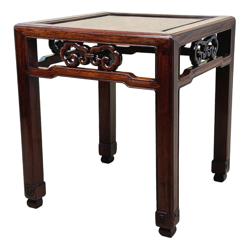 A dark brown square oriental hardwood side table featuring carved scrollwork aprons and straight legs with carved feet.