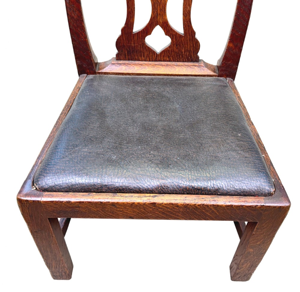 A 19th-century Georgian style childs chair crafted in dark oak with a pierced fretwork back splat and a dark leather drop-in seat. View III