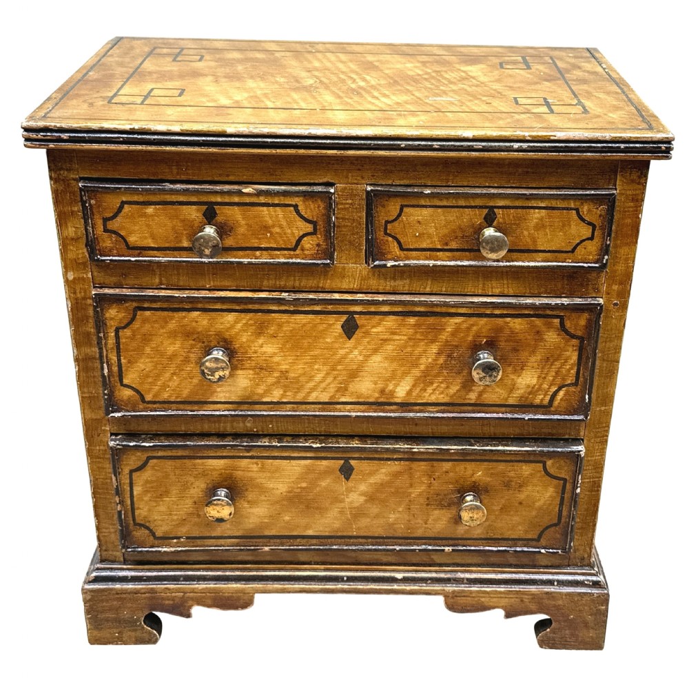 A 19th-century miniature pine chest of drawers with grain-painted finish, black line borders, and bracket feet. View IX