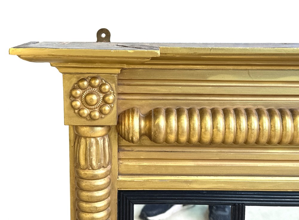 A 19th-century Regency style giltwood overmantel mirror with a three-panel glass layout, reeded frame, and ebonised inner border. View II