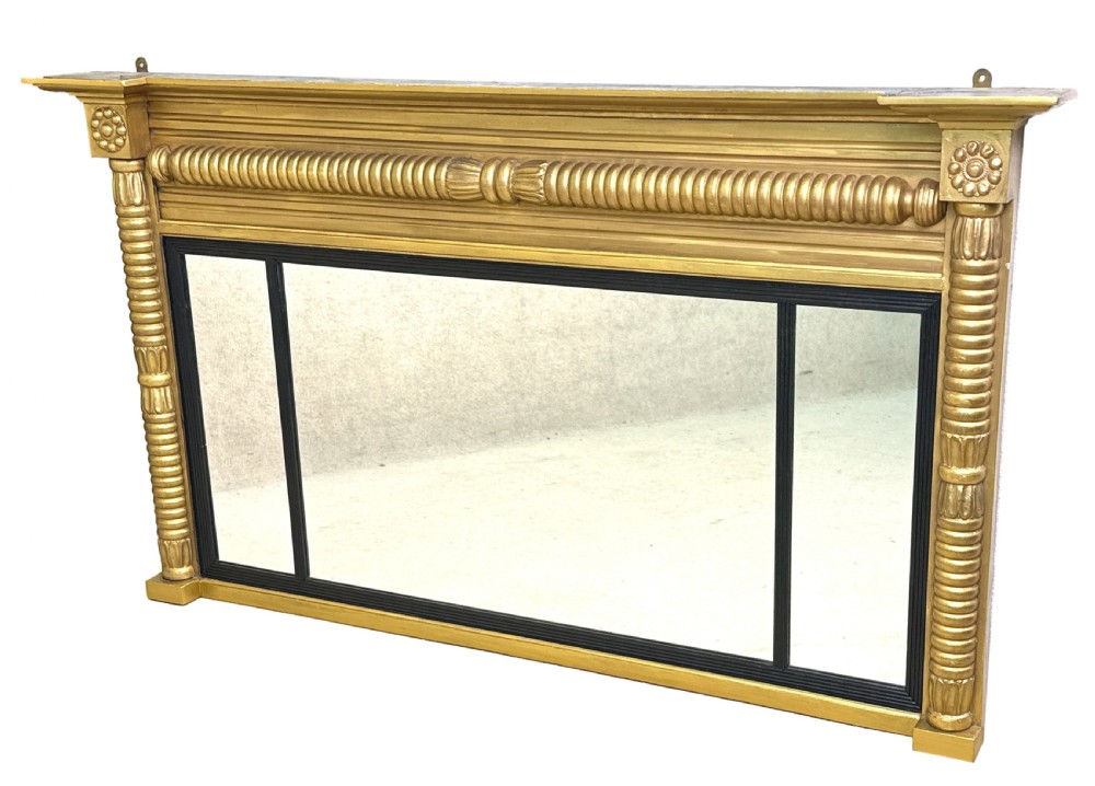 A 19th-century Regency style giltwood overmantel mirror with a three-panel glass layout, reeded frame, and ebonised inner border. View IX