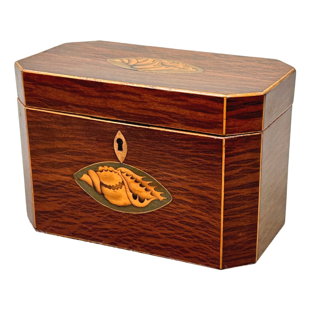 An octagonal wooden tea caddy in warm brown timber featuring marquetry shell inlays on the top and front panel with fine edge stringing.