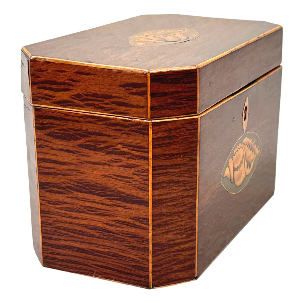An octagonal wooden tea caddy in warm brown timber featuring marquetry shell inlays on the top and front panel with fine edge stringing. View II