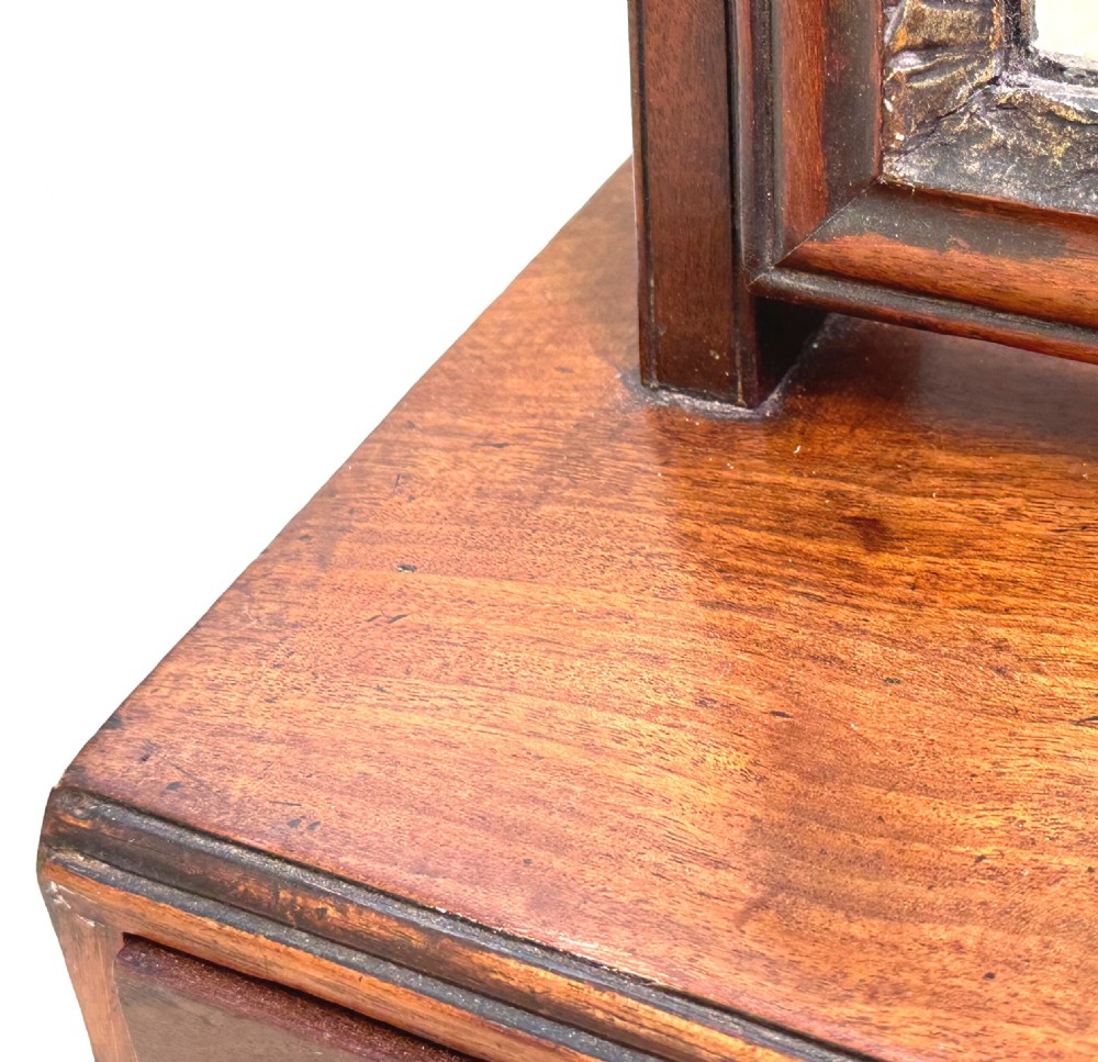 An antique Georgian mahogany toilet mirror featuring a pivoting arched glass frame set above a box base with three drawers and brass fittings. View VI