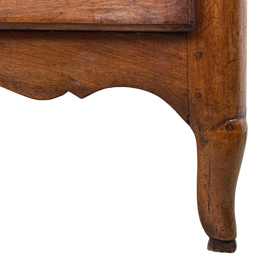 An 18th-century French provincial walnut commode chest featuring three full-width drawers decorated with elaborate brass handles and keyhole escutcheons, set above a scalloped apron and short cabriole legs. View XIII