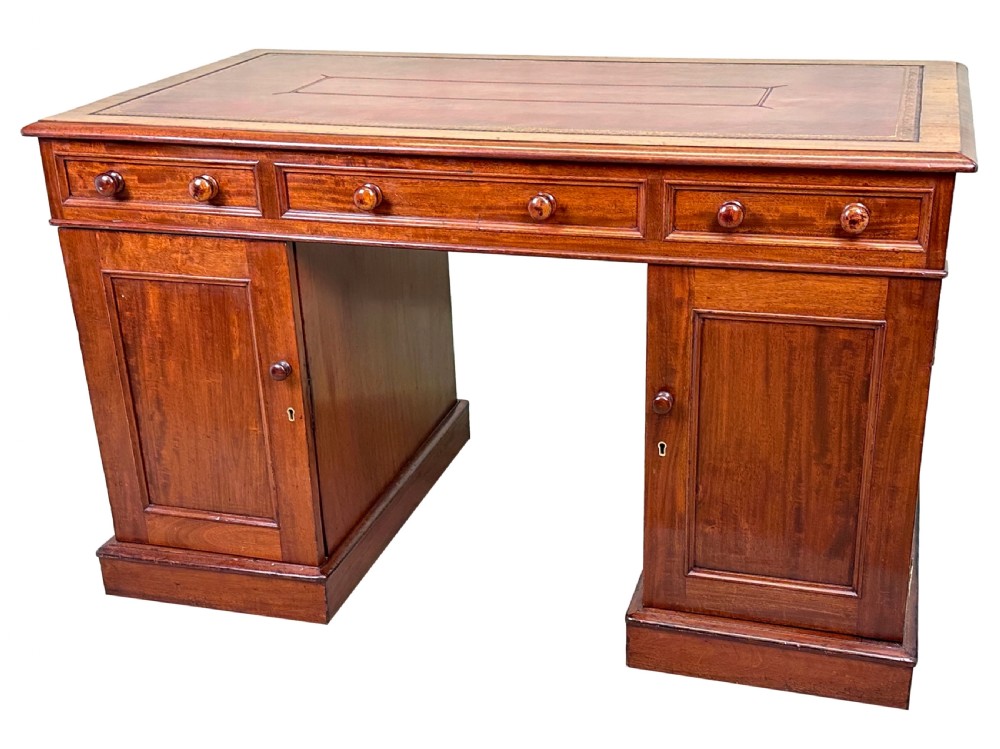An antique Regency mahogany pedestal desk featuring a gold-tooled leather writing inset and multiple drawers with turned wooden handles on plinth bases. View III
