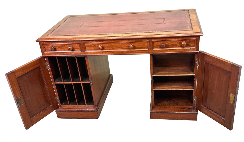 An antique Regency mahogany pedestal desk featuring a gold-tooled leather writing inset and multiple drawers with turned wooden handles on plinth bases. View XI