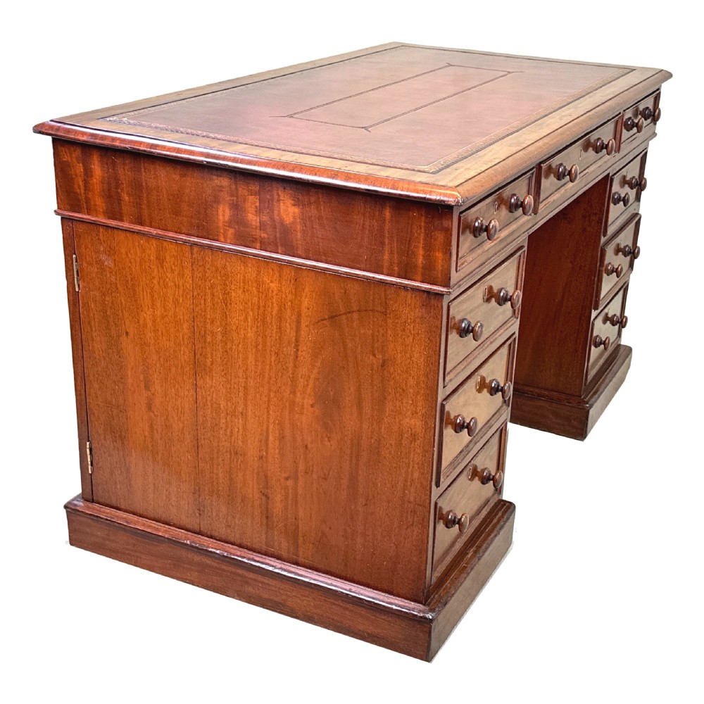An antique Regency mahogany pedestal desk featuring a gold-tooled leather writing inset and multiple drawers with turned wooden handles on plinth bases. View XIV