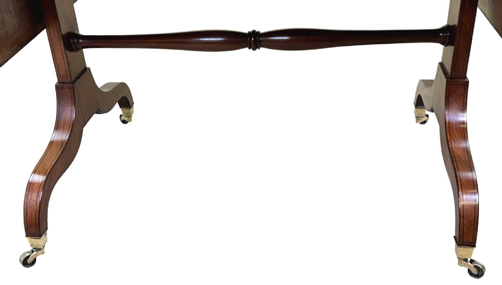 A 19th-century Regency mahogany sofa table featuring two drop leaves, two frieze drawers with octagonal brass handles, a turned stretcher, and splay legs on brass castors. View VII