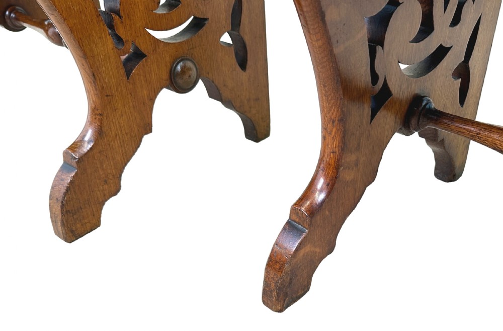 A matched pair of 19th-century carved oak hall seats featuring arched top handle rails, shield-carved back panels, pierced side aprons, and turned cross stretchers. View VI