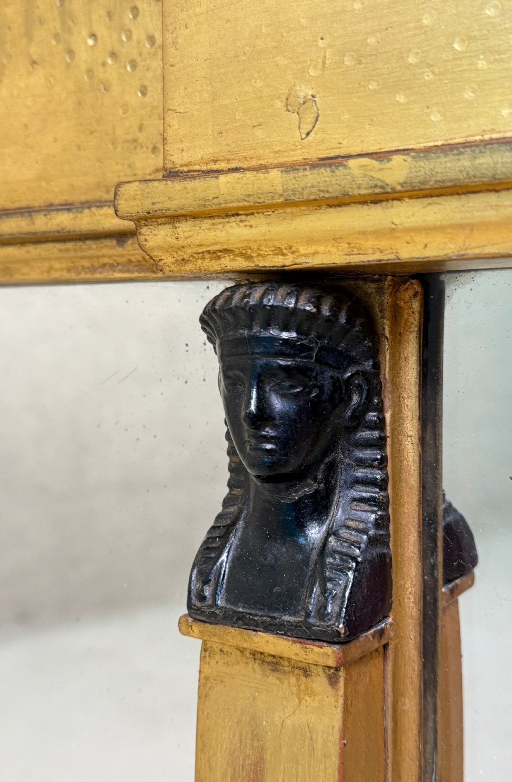 A wide Regency giltwood overmantel mirror featuring three mirror plates, ball moulding along the top cornice, central carved shell frieze, and black Egyptian head pilasters. View II