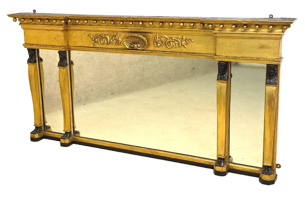 A wide Regency giltwood overmantel mirror featuring three mirror plates, ball moulding along the top cornice, central carved shell frieze, and black Egyptian head pilasters. View XII