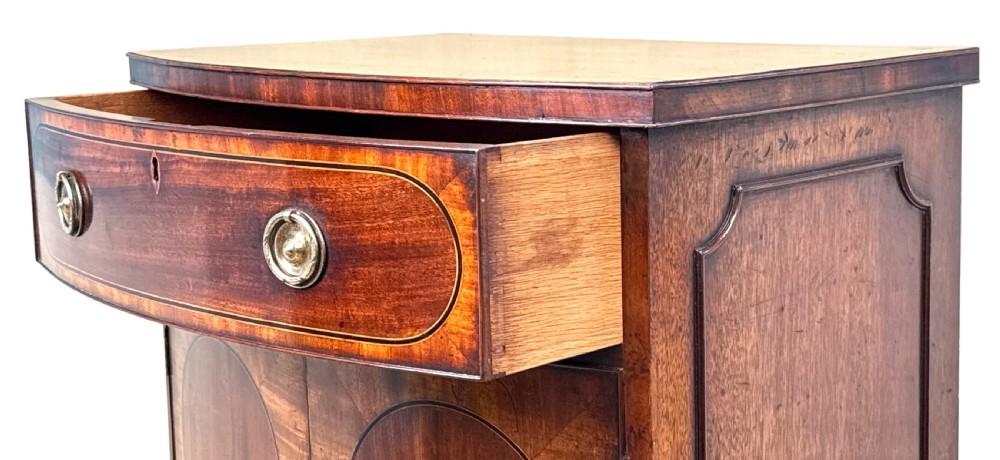 An 18th-century Georgian mahogany bowfront side cupboard featuring two arched inlaid doors, a top frieze drawer with brass handles, and splay feet. View IV