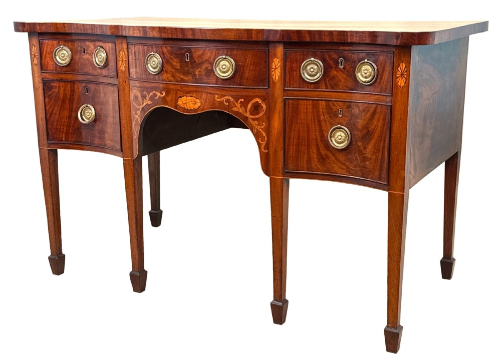 A small Georgian mahogany sideboard featuring a serpentine front, floral marquetry inlay, multiple drawers with brass ring handles, and tapered square legs with spade feet.