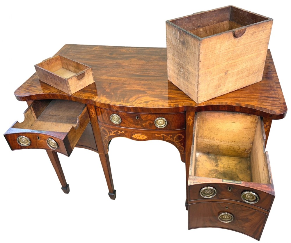 A small Georgian mahogany sideboard featuring a serpentine front, floral marquetry inlay, multiple drawers with brass ring handles, and tapered square legs with spade feet. View III
