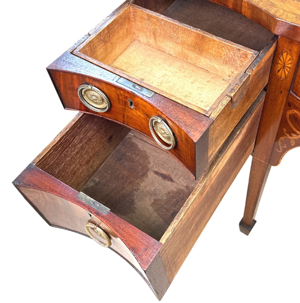 A small Georgian mahogany sideboard featuring a serpentine front, floral marquetry inlay, multiple drawers with brass ring handles, and tapered square legs with spade feet. View V