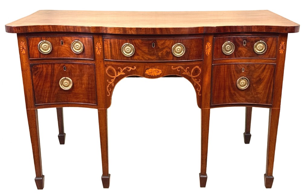 A small Georgian mahogany sideboard featuring a serpentine front, floral marquetry inlay, multiple drawers with brass ring handles, and tapered square legs with spade feet. View XIV