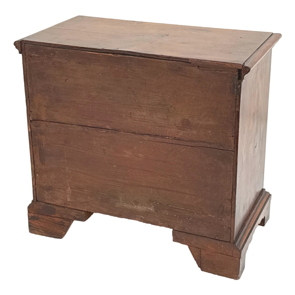 A Georgian miniature yew wood chest of four drawers featuring brass knobs, a keyhole escutcheon, and bracket feet. View IX