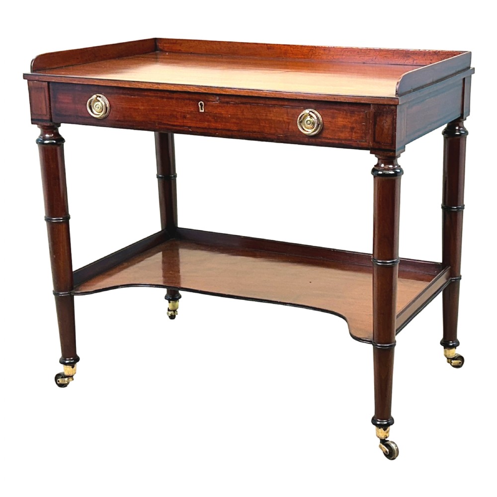 A 19th-century Georgian mahogany dressing table featuring a raised gallery top, single drawer with brass ring handles, undershelf, turned legs, and brass castors.