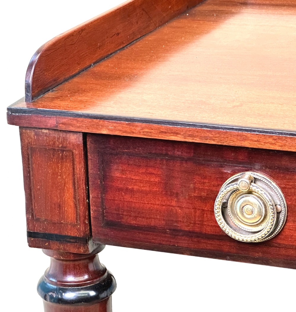 A 19th-century Georgian mahogany dressing table featuring a raised gallery top, single drawer with brass ring handles, undershelf, turned legs, and brass castors. View II