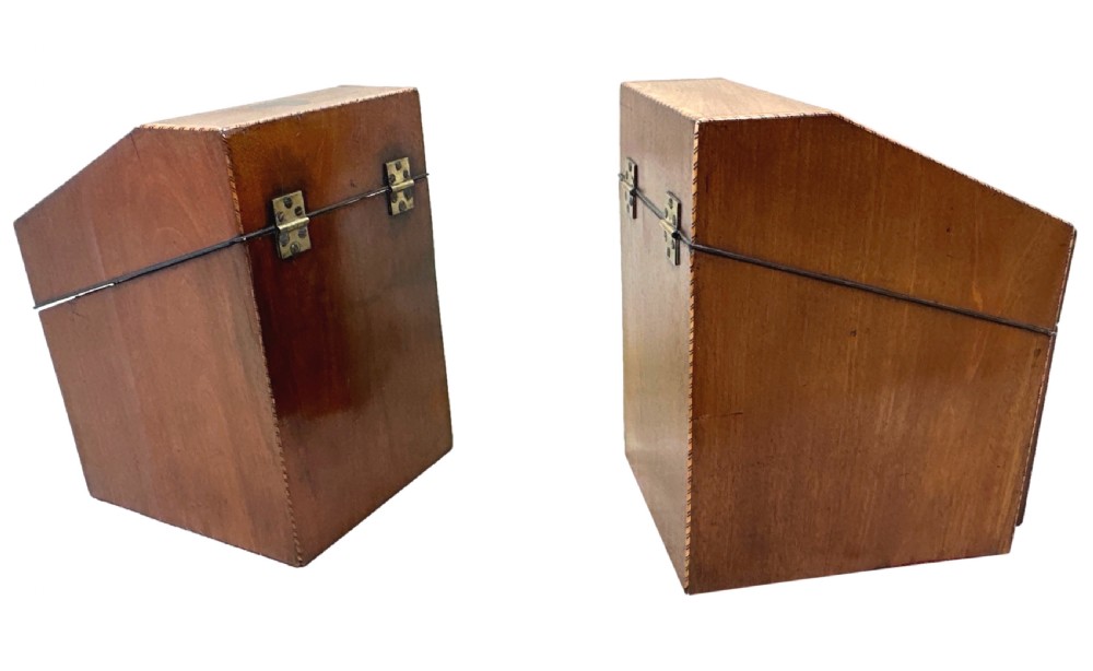 A pair of Georgian mahogany knife boxes featuring sloping lids with inlaid shell motifs, serpentine fronts, and metal keyhole escutcheons. View V