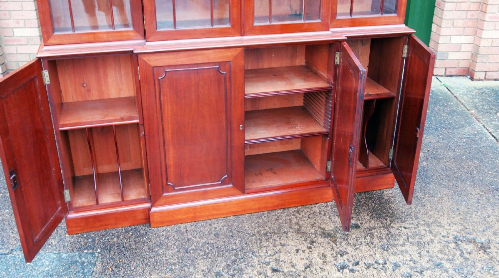 A Georgian mahogany breakfront bookcase featuring astragal glazed upper doors with Gothic arch tracery above panelled lower cupboards. View V