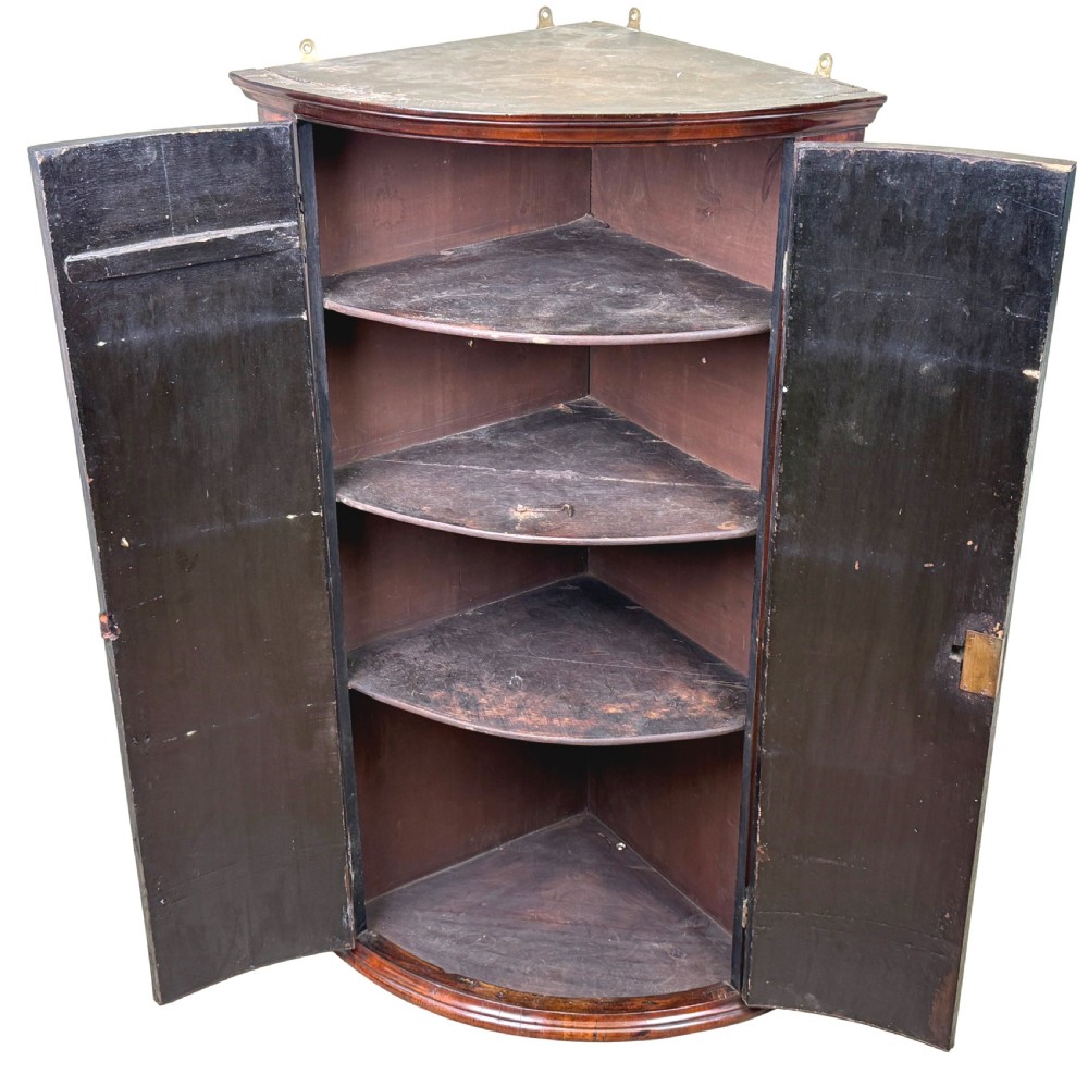 A bow-fronted Georgian corner cupboard featuring highly figured burr walnut veneers, inlaid crossbanding, double arched panelled doors, and shaped brass hinges. View III