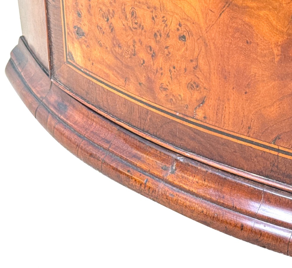 A bow-fronted Georgian corner cupboard featuring highly figured burr walnut veneers, inlaid crossbanding, double arched panelled doors, and shaped brass hinges. View IX