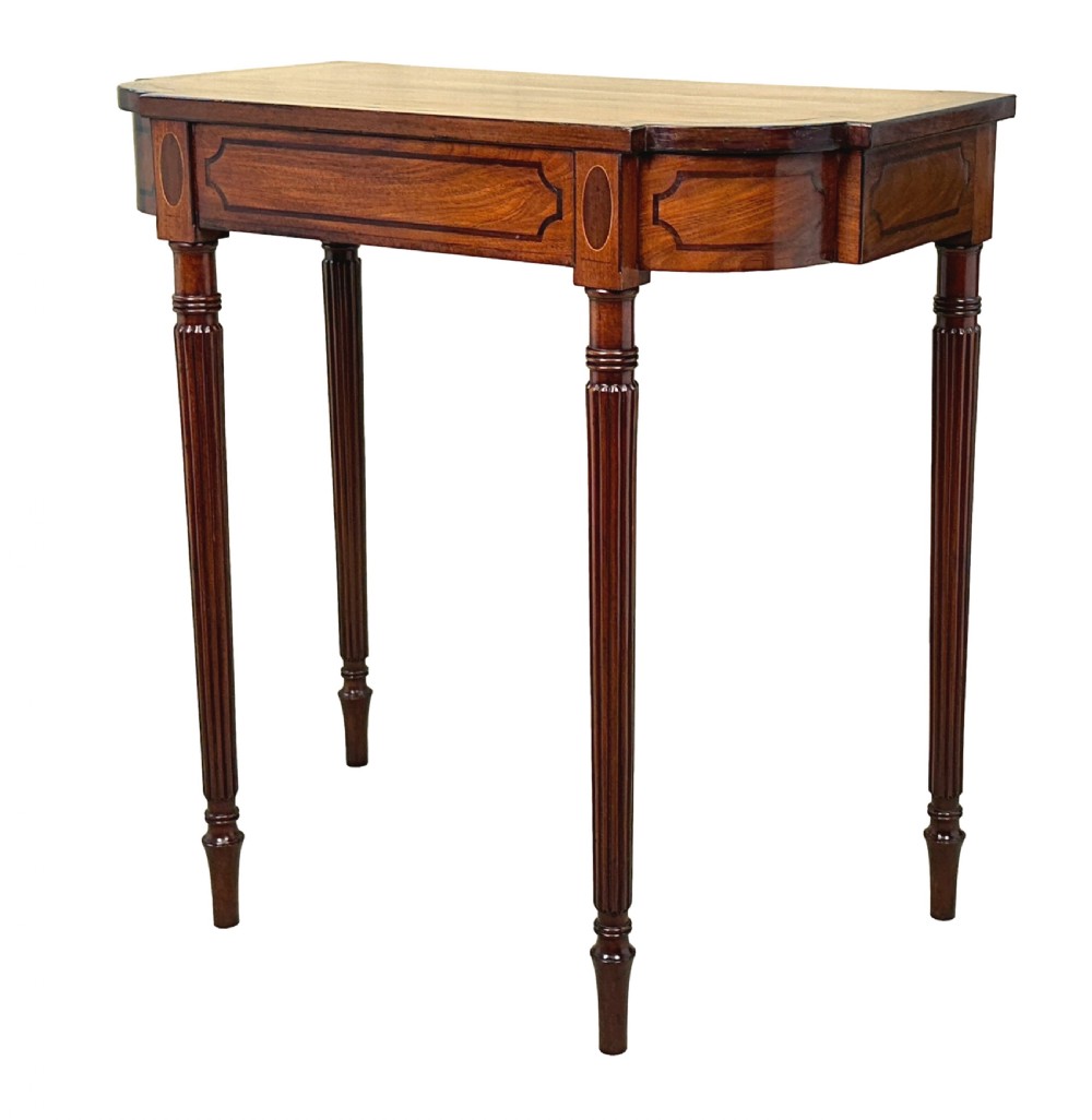 A Regency mahogany console table featuring reeded tapering legs, a shaped apron, and boxwood inlay detail.