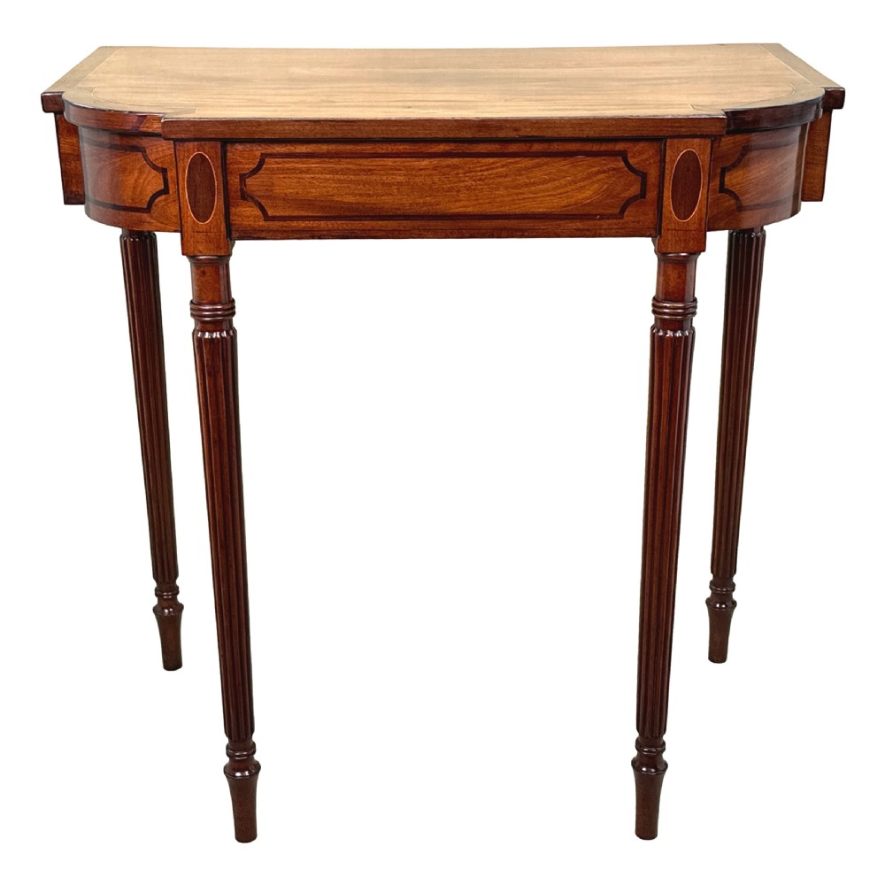 A Regency mahogany console table featuring reeded tapering legs, a shaped apron, and boxwood inlay detail. View X