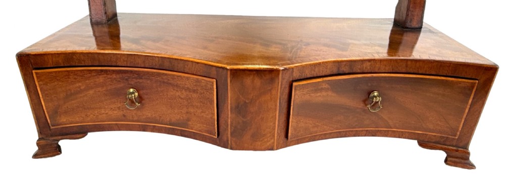 A Georgian mahogany dressing table mirror featuring a shield-shaped swivel mirror on shaped uprights above a serpentine base with two drawers. View V