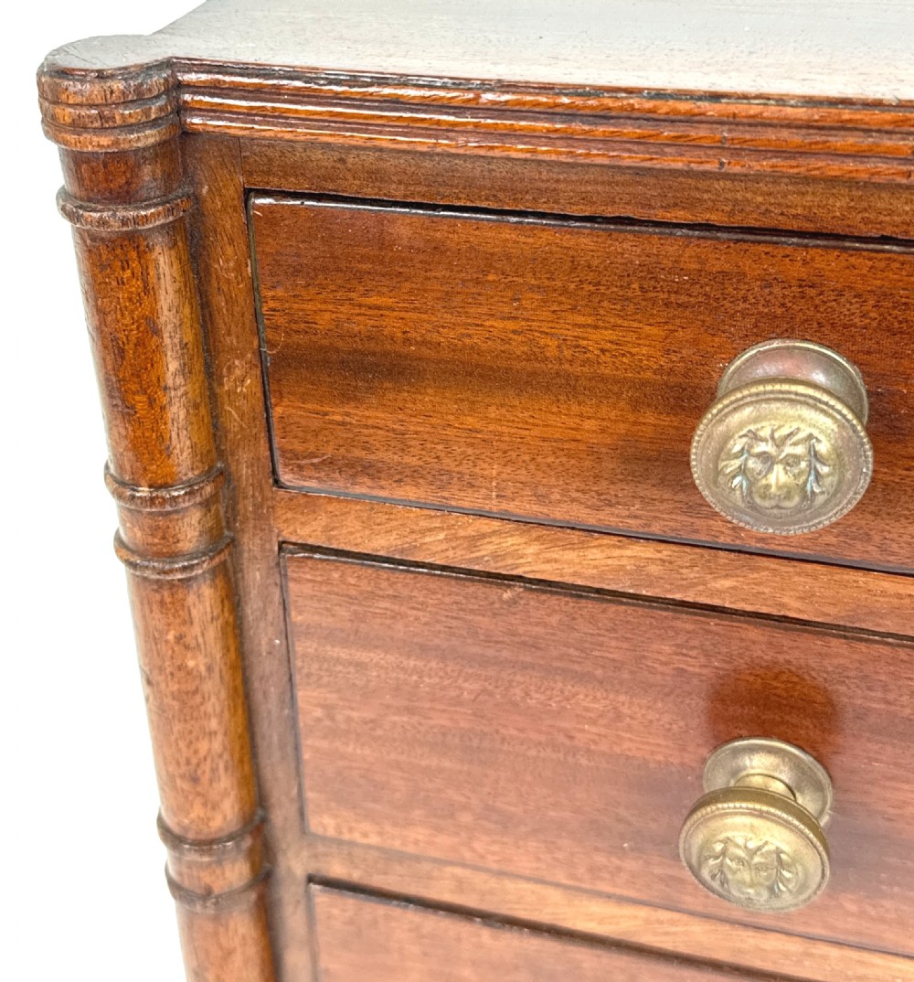 A Regency period miniature mahogany chest featuring three graduated drawers with round knobs and reeded corner columns. View III