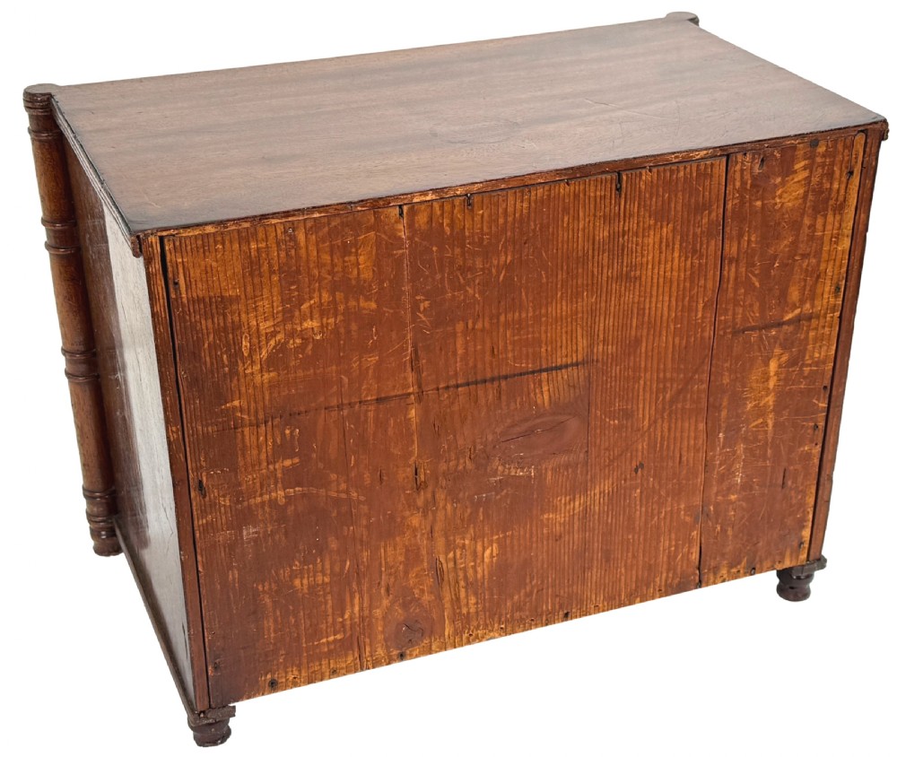 A Regency period miniature mahogany chest featuring three graduated drawers with round knobs and reeded corner columns. View VII