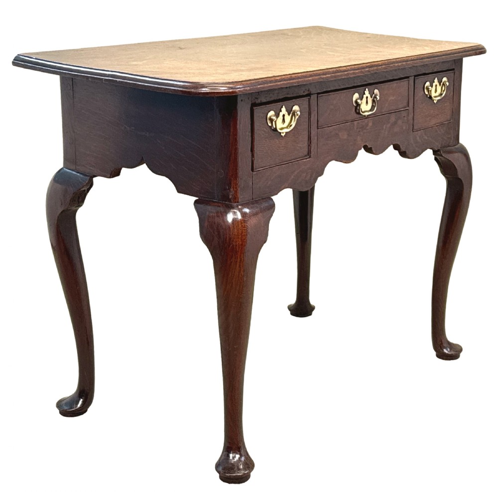 An 18th-century Georgian oak lowboy featuring three drawers with brass handles, a shaped apron, and four cabriole legs with pad feet. View II