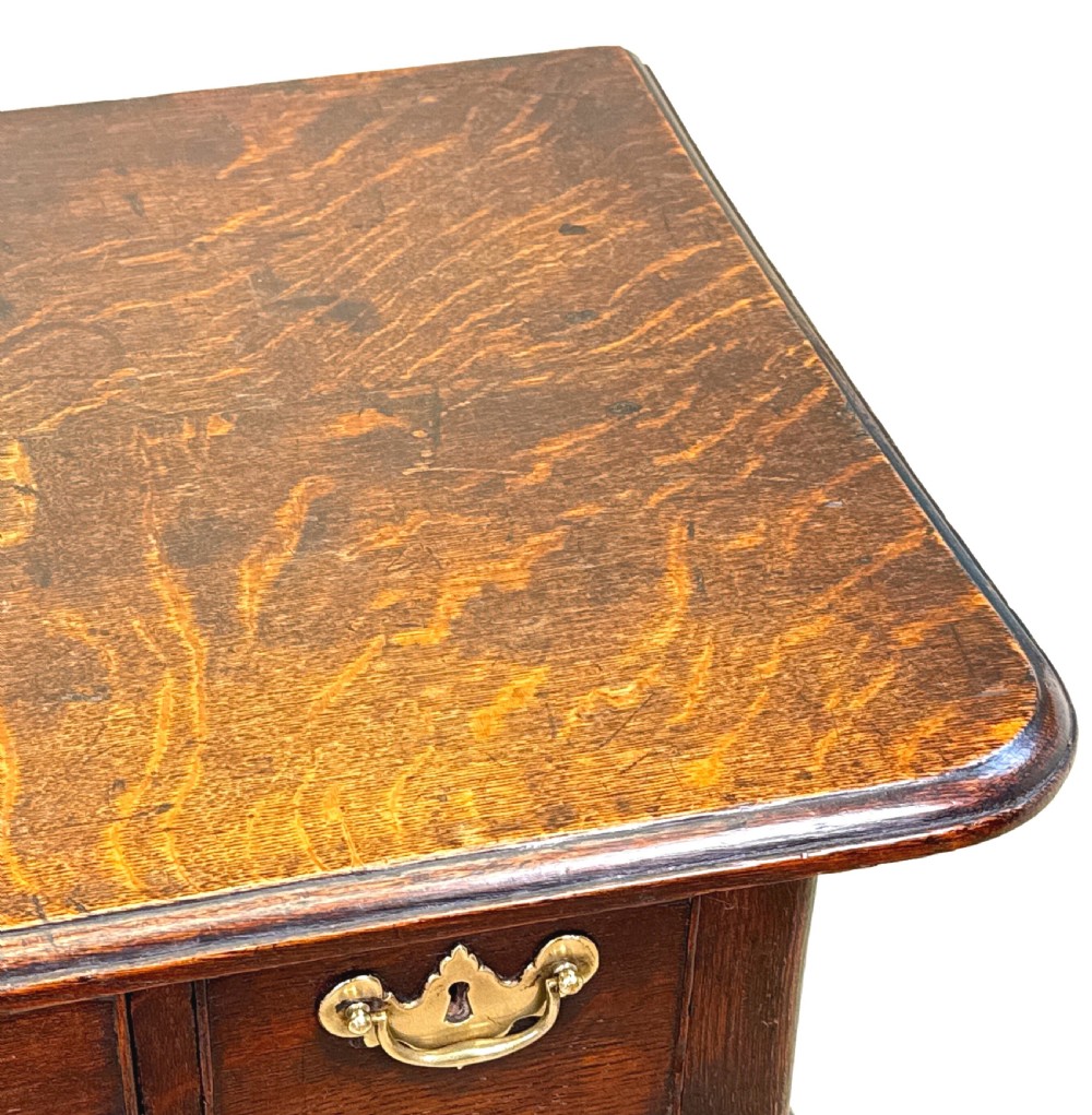 An 18th-century Georgian oak lowboy featuring three drawers with brass handles, a shaped apron, and four cabriole legs with pad feet. View V