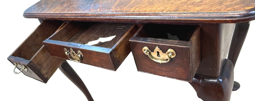An 18th-century Georgian oak lowboy featuring three drawers with brass handles, a shaped apron, and four cabriole legs with pad feet. View VII
