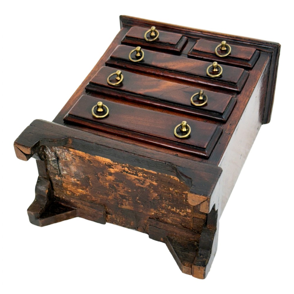 A miniature 18th-century mahogany chest of drawers featuring two small drawers over three long drawers with brass ring drop handles and bracket feet. View VII