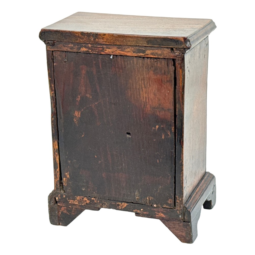 A miniature 18th-century mahogany chest of drawers featuring two small drawers over three long drawers with brass ring drop handles and bracket feet. View VIII