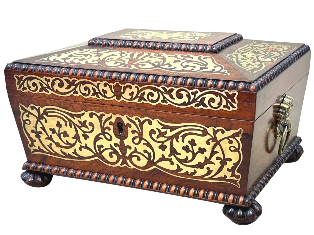 A Regency rosewood sarcophagus-shaped work box with brass foliate inlay, gadrooned mouldings, side handles, and carved feet.