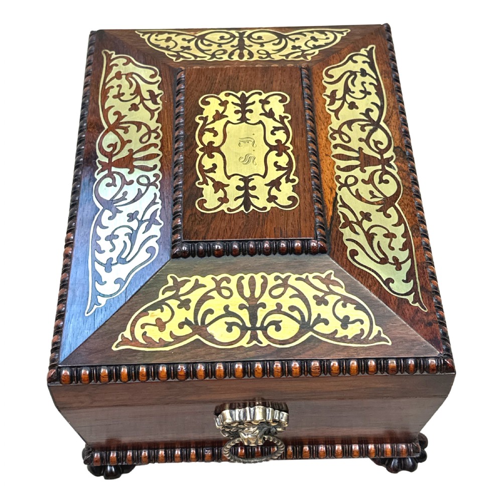 A Regency rosewood sarcophagus-shaped work box with brass foliate inlay, gadrooned mouldings, side handles, and carved feet. View V