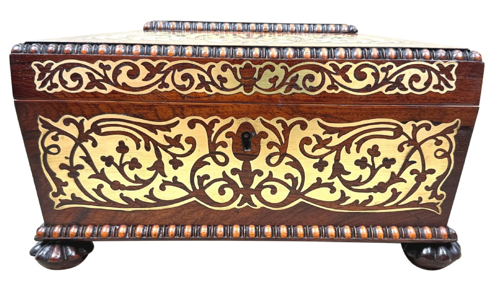 A Regency rosewood sarcophagus-shaped work box with brass foliate inlay, gadrooned mouldings, side handles, and carved feet. View XIV