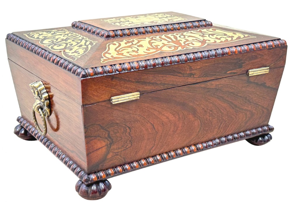 A Regency rosewood sarcophagus-shaped work box with brass foliate inlay, gadrooned mouldings, side handles, and carved feet. View XV