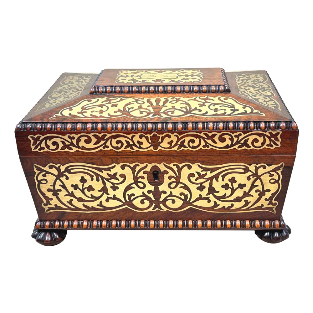 A Regency rosewood sarcophagus-shaped work box with brass foliate inlay, gadrooned mouldings, side handles, and carved feet. View XVII